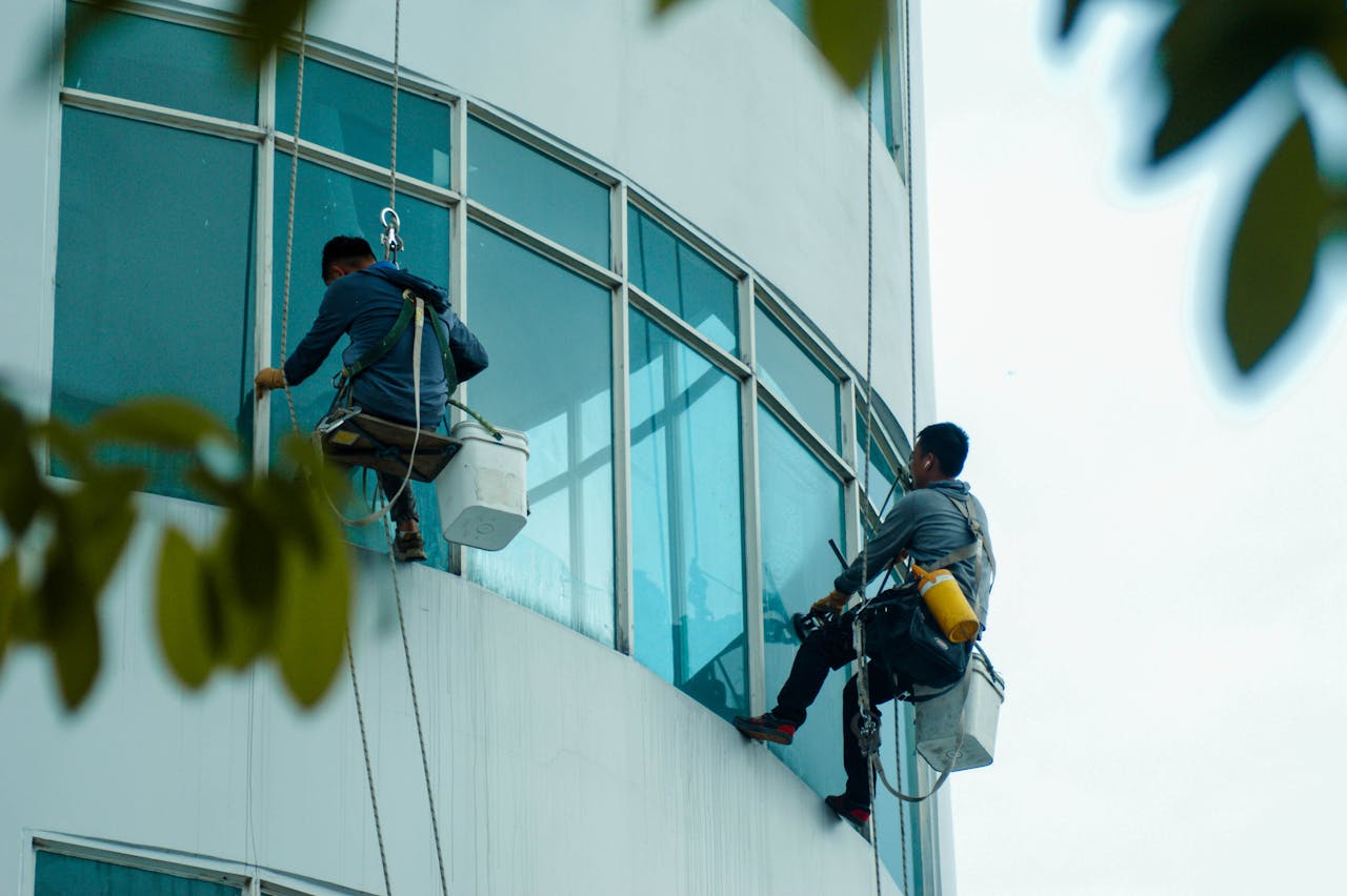 gallery-1 Window cleaners suspended on ropes clean a high-rise building's glass exterior.